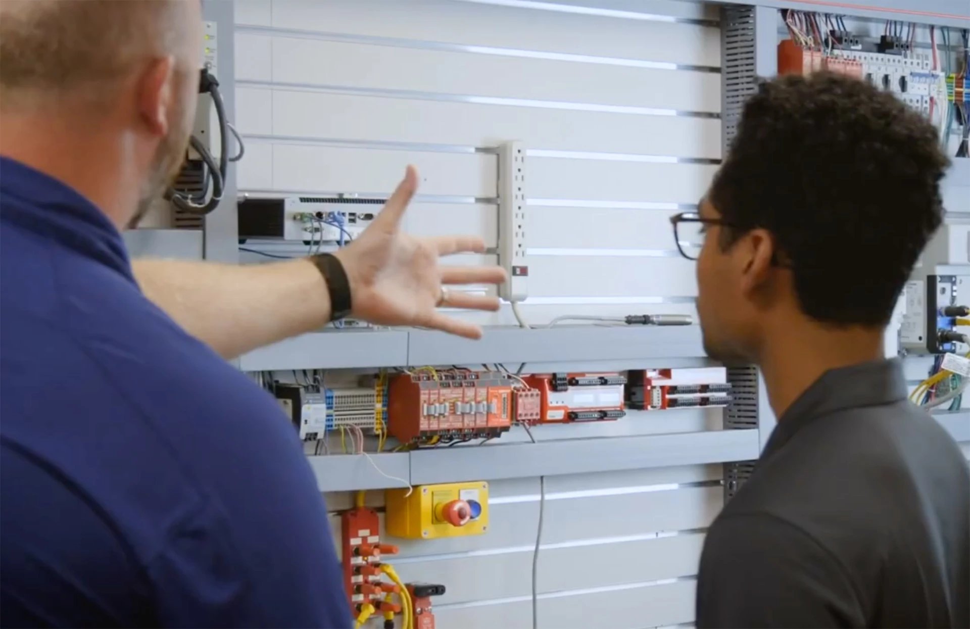 Solution Consultant discussing technology with customer in front of Automation Wall