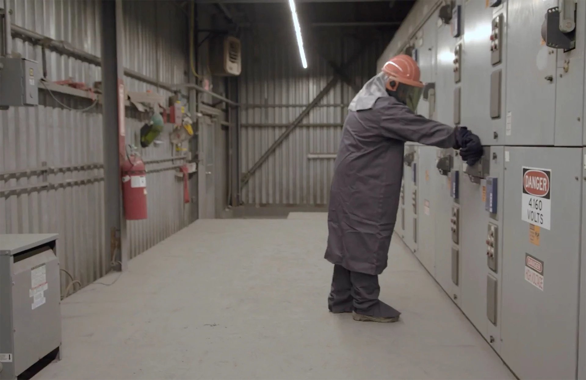 Worker in full PPE in front of switchgear