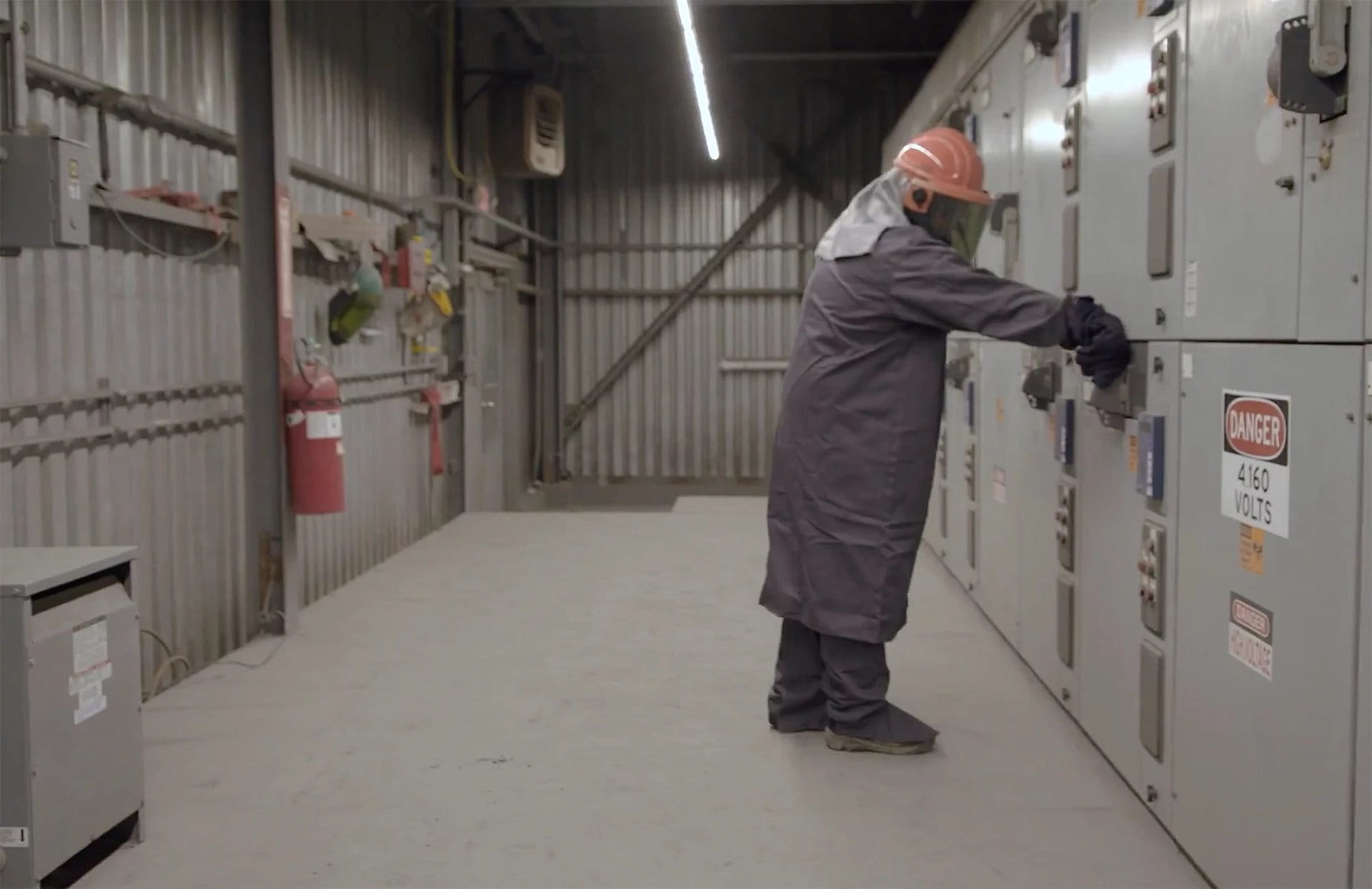 Worker in full PPE in front of switchgear